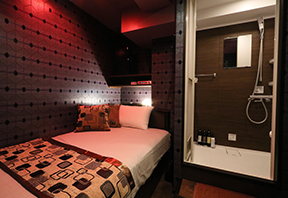 Room with a bed and its own glass shower booth