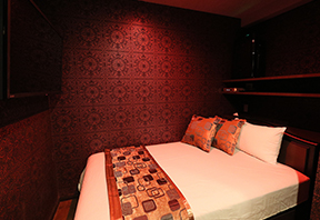 Private room with a double bed, patterned bed runner and cushions