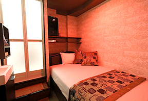 Room with bed, cushions and wall-mounted TV